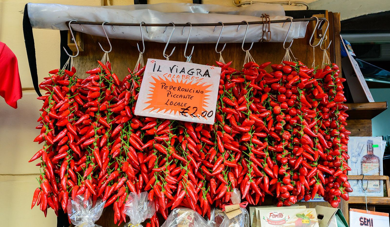Trecce di peperoncini rossi calabresi appese in un mercato